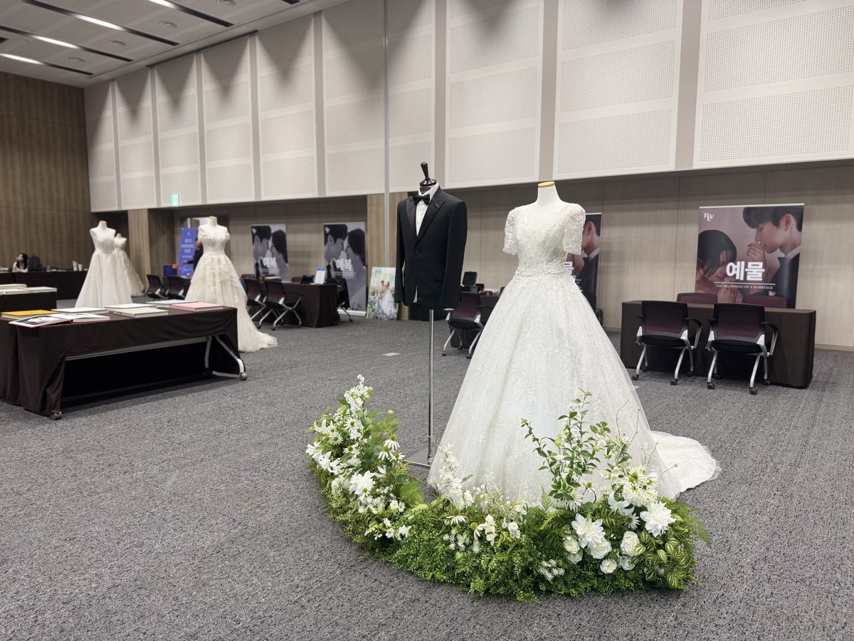 Floral and botanical decor arranged around a wedding dress backdrop